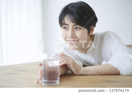 A young woman going about her daily life, drinking water and relaxing in her living room. A young woman going about her daily life, drinking water and relaxing in her living room. 137974279