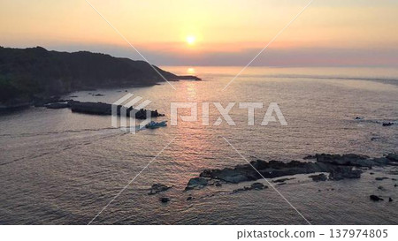 A fishing boat sailing across the sea bathed in the setting sun. Aerial view of the area around Susaki on the Izu Peninsula. 137974805