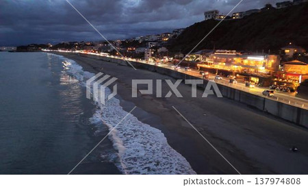 Shichirigahama Beach at night. A restaurant lit up and the shimmering waves (drone footage). 137974808
