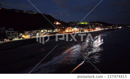 Shichirigahama Beach at night. A restaurant lit up and the shimmering waves (drone footage). Shichirigahama Beach at night. A restaurant lit up and the shimmering waves (drone footage). 137974815