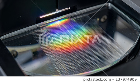 Close-up of a diffraction grating splitting white light into a vibrant rainbow spectrum, perfect for science, optics, and physics concepts 137974909