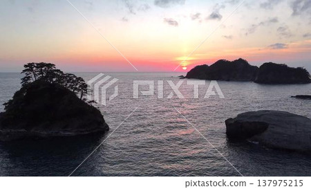 Dogashima during magic hour. A fantastical sunset sky and the silhouette of the island (aerial view). 137975215