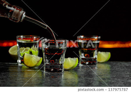 Strong alcoholic drink and lime slices on a black background. 137975787