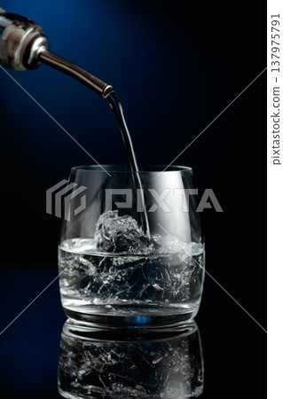 Crystal clear vodka being poured over ice in a glass. 137975791