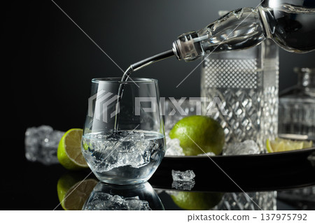 Vodka or gin is poured into a glass with ice. 137975792