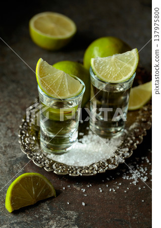 Tequila with salt and lime slices on a silver tray. 137975800