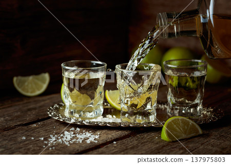 Tequila with salt and lime slices on a silver tray. 137975803