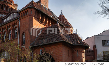 Historic Red Brick Facade with Turrets and Tiled Roofs 137975840