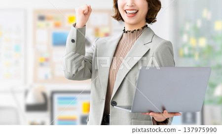 A woman/businesswoman doing a fist pump while holding a computer 137975990