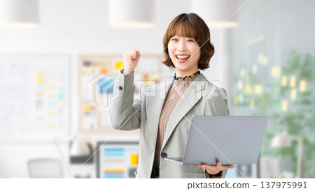 一位女性/女商人一邊揮拳一邊拿著電腦 137975991