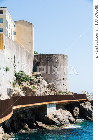 清澈湛藍的海水和沿海矗立的歷史悠久的石頭建築-位於地中海的法國科西嘉島。 清澈湛藍的海水和沿海矗立的歷史悠久的石頭建築-位於地中海的法國科西嘉島。 137976089