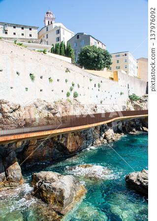 Crystal-clear blue seas and historic stone buildings standing along the coastline – on the French island of Corsica in the Mediterranean Sea. Crystal-clear blue seas and historic stone buildings standing along the coastline – on the French island of Corsica in the Mediterranean Sea. 137976092