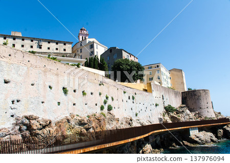 Crystal-clear blue seas and historic stone buildings standing along the coastline – on the French island of Corsica in the Mediterranean Sea. 137976094