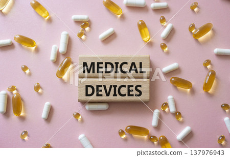 MEDICAL DEVICES symbol. Concept word MEDICAL DEVICES on wooden blocks. Beautiful pink background with pills. Medicine and MEDICAL DEVICES. Copy space MEDICAL DEVICES symbol. Concept word MEDICAL DEVICES on wooden blocks. Beautiful pink background with pills. Medicine and MEDICAL DEVICES. Copy space 137976943