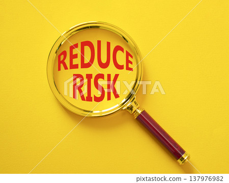 Reduce Risk symbol. Magnifying Glass with words Reduce Risk. Businessman hand. Beautiful yellow background. Business and Reduce Risk concept. Copy space. Reduce Risk symbol. Magnifying Glass with words Reduce Risk. Businessman hand. Beautiful yellow background. Business and Reduce Risk concept. Copy space. 137976982