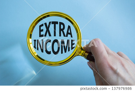 Extra Income symbol. Magnifying Glass with words Extra Income. Businessman hand. Beautiful blue background. Business and Extra Income concept. Copy space. Extra Income symbol. Magnifying Glass with words Extra Income. Businessman hand. Beautiful blue background. Business and Extra Income concept. Copy space. 137976986