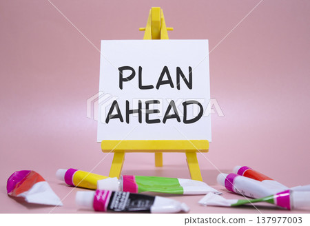 Plan ahead symbol. Wooden blocks with words Plan ahead. Beautiful pink background with paints and easel. Business and Plan ahead concept. Copy space. Plan ahead symbol. Wooden blocks with words Plan ahead. Beautiful pink background with paints and easel. Business and Plan ahead concept. Copy space. 137977003