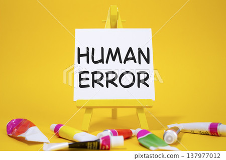 Human Error symbol. Concept word Human Error on wooden blocks. Beautiful yellow background with paints and easel. Medicine and Human Error concept. Copy space 137977012