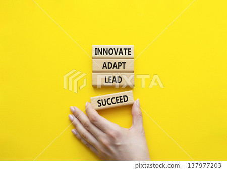 Innovate Adapt Lead Succeed symbol. Concept words Innovate Adapt Lead Succeed on wooden blocks. Beautiful bright yellow background. Businessman hand. Business and Innovate Adapt Lead Succeed concept. 137977203