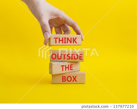 THINK OUTSIDE THE BOX symbol. Wooden blocks with words THINK OUTSIDE THE BOX. Businessman hand. Beautiful yellow background. Business and THINK OUTSIDE THE BOX concept. Copy space 137977210