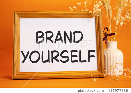 Brand yourself symbol. Concept words Brand yourself on beautiful wooden picture frame. Beautiful orange background with flower vase. Business and Brand yourself concept. Copy space. Brand yourself symbol. Concept words Brand yourself on beautiful wooden picture frame. Beautiful orange background with flower vase. Business and Brand yourself concept. Copy space. 137977286