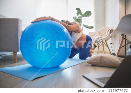 Pregnant woman exercising with fitness ball at home Pregnant woman exercising with fitness ball at home 137977472