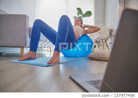 Pregnant woman exercising at home using an exercise ball 137977486