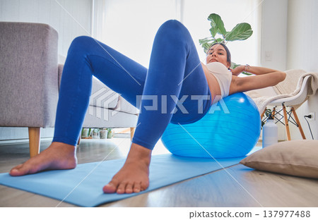 Pregnant woman exercising at home using an exercise ball 137977488