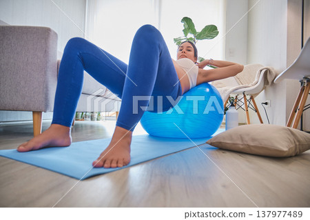 Pregnant woman exercising at home on a fitness ball Pregnant woman exercising at home on a fitness ball 137977489
