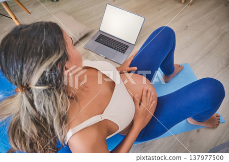 Pregnant woman exercising at home during prenatal fitness class Pregnant woman exercising at home during prenatal fitness class 137977500