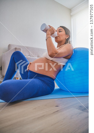 Pregnant woman hydrating during prenatal exercise at home Pregnant woman hydrating during prenatal exercise at home 137977505