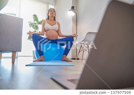 Pregnant woman practicing yoga and meditation at home Pregnant woman practicing yoga and meditation at home 137977509