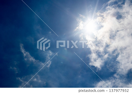 A landscape of dazzling sunlight and white clouds. 137977932