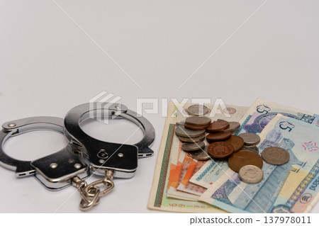 Handcuffs and British pounds reflecting confiscation fines and financial sanctions Handcuffs and British pounds reflecting confiscation fines and financial sanctions 137978011