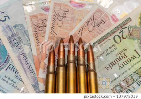 Row of cartridges on pound sterling showing military spending and financial risks 137978019