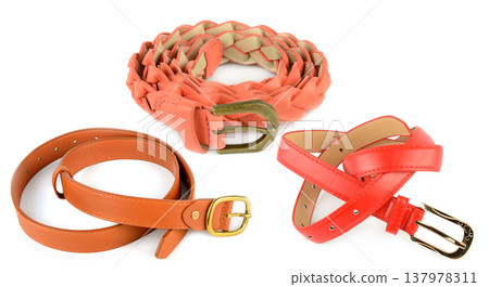 Elegant female fashion accessories set featuring a braided peach belt and classic leather waistbands in autumn tones arranged on a clean white surface for commercial retail. Elegant female fashion accessories set featuring a braided peach belt and classic leather waistbands in autumn tones arranged on a clean white surface for commercial retail. 137978311