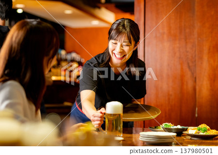 A woman working as a server at an izakaya (Japanese pub). 137980501