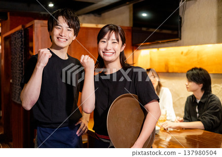 A woman working as a server at an izakaya (Japanese pub). A woman working as a server at an izakaya (Japanese pub). 137980504