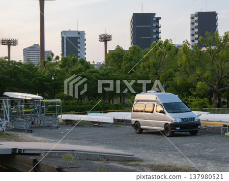 A silver van parked at the boat dock and the surrounding cityscape. A silver van parked at the boat dock and the surrounding cityscape. 137980521