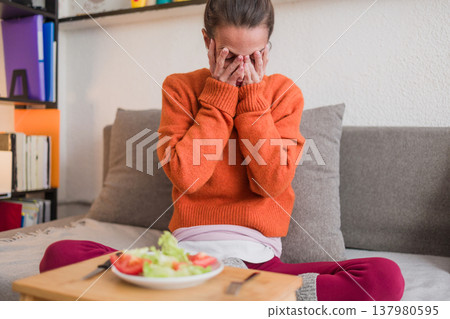 Woman struggling with eating disorder showing distress about food 137980595