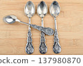 Vintage silver plated teaspoons with intricate patterns on wood. 137980870