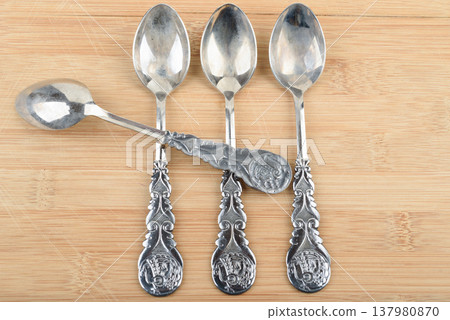 Vintage silver plated teaspoons with intricate patterns on wood. 137980870