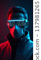 Modern IT specialist in protective mask with glasses reflecting program code under neon lighting. 137981265