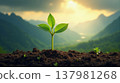 Vibrant green seedling breaking through fertile soil against majestic mountains and rising sun rays symbolizing new life and nature rebirth. 137981268