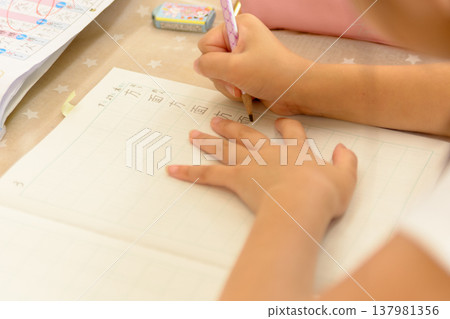 Elementary school student practicing kanji: close-up of their hands during study. Elementary school student practicing kanji: close-up of their hands during study. 137981356