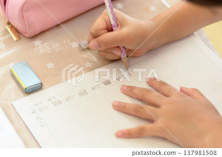 A child writing kanji in a notebook; a primary school student's hands while studying. 137981508