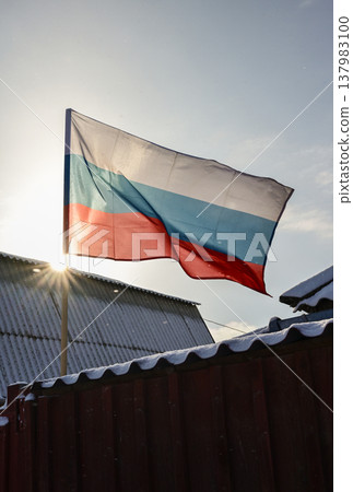 A Russian federation flag waving on the house roof. The Russian Federation state flag is rectangular in form and comprises three equal horizontal stripes. 137983100