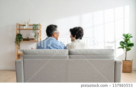 Back view of a senior Japanese man and woman relaxing in their living room (AI-generated image) 137983553