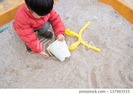 A boy playing in a sandbox 137983555