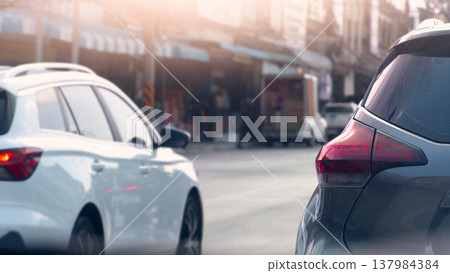 Rear side of car driving on the asphalt road in the city. Emitting visible exhaust smoke into the city air. Captures the environmental impact of daily commuting and traffic congestion. 137984384